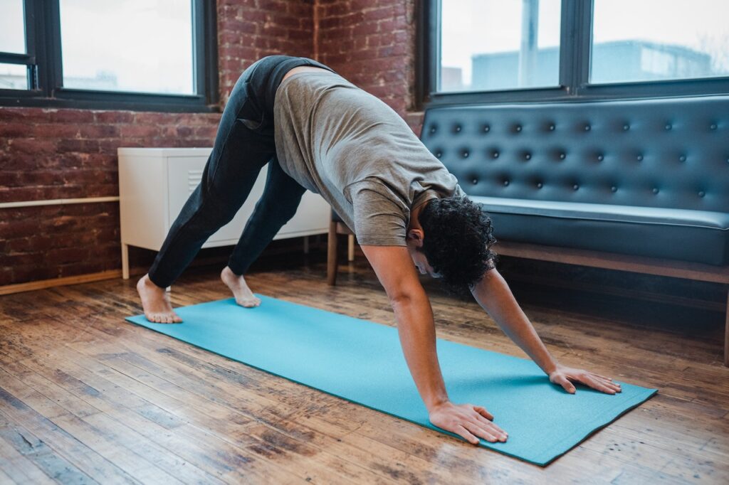 Man practicing yoga in downward dog pose during a mindful wellness retreats session