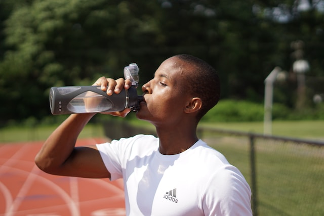 A man hydrating with water during a workout, demonstrating the healthy habit of proper water intake and rest during exercise.